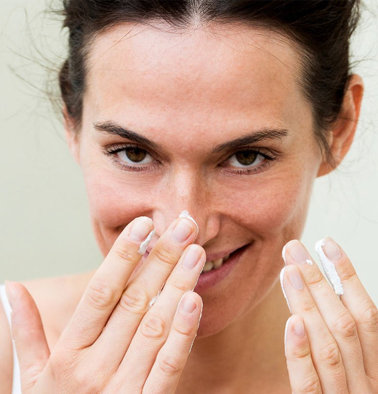 Frau berührt lächelnd ihre Haut